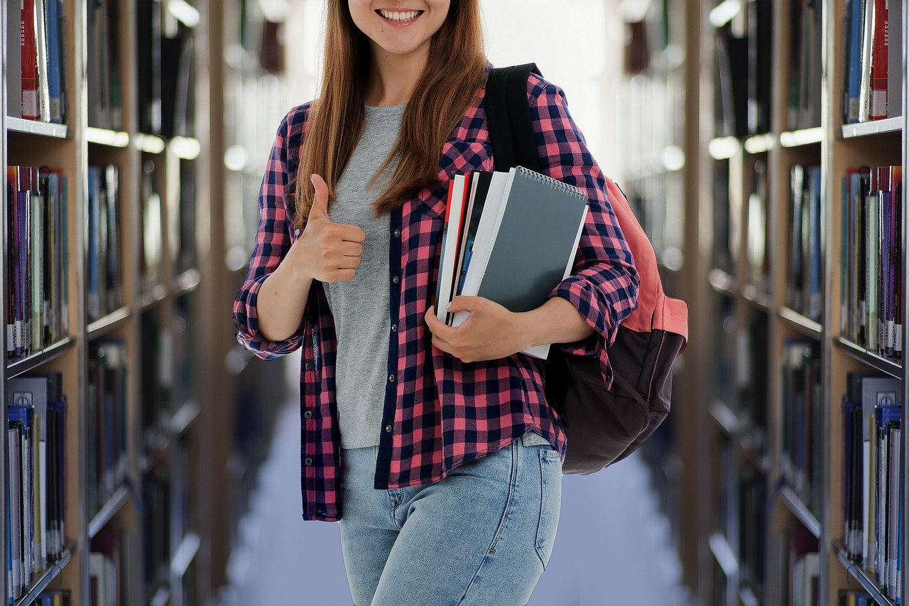 Studentin in der Bibliothek zeigt den Daumen hoch.